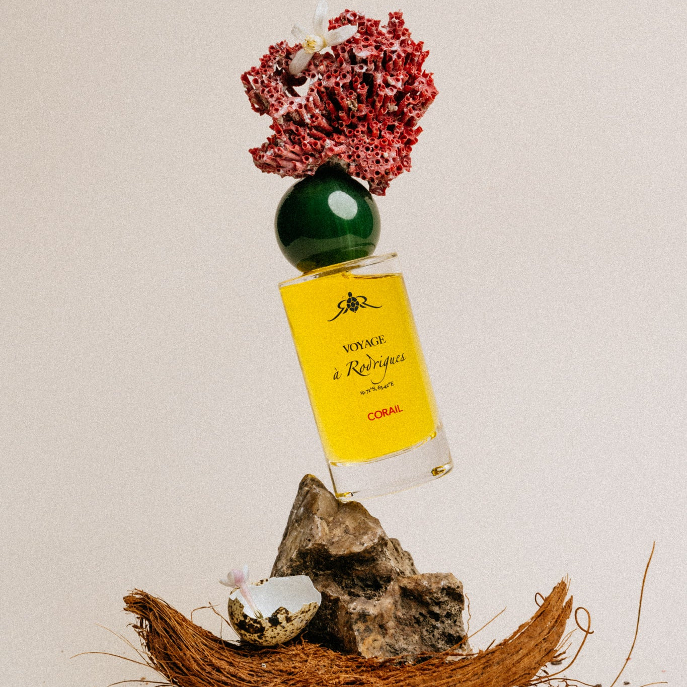 Corail - Perfume bottle with flowers and rocks on a neutral background