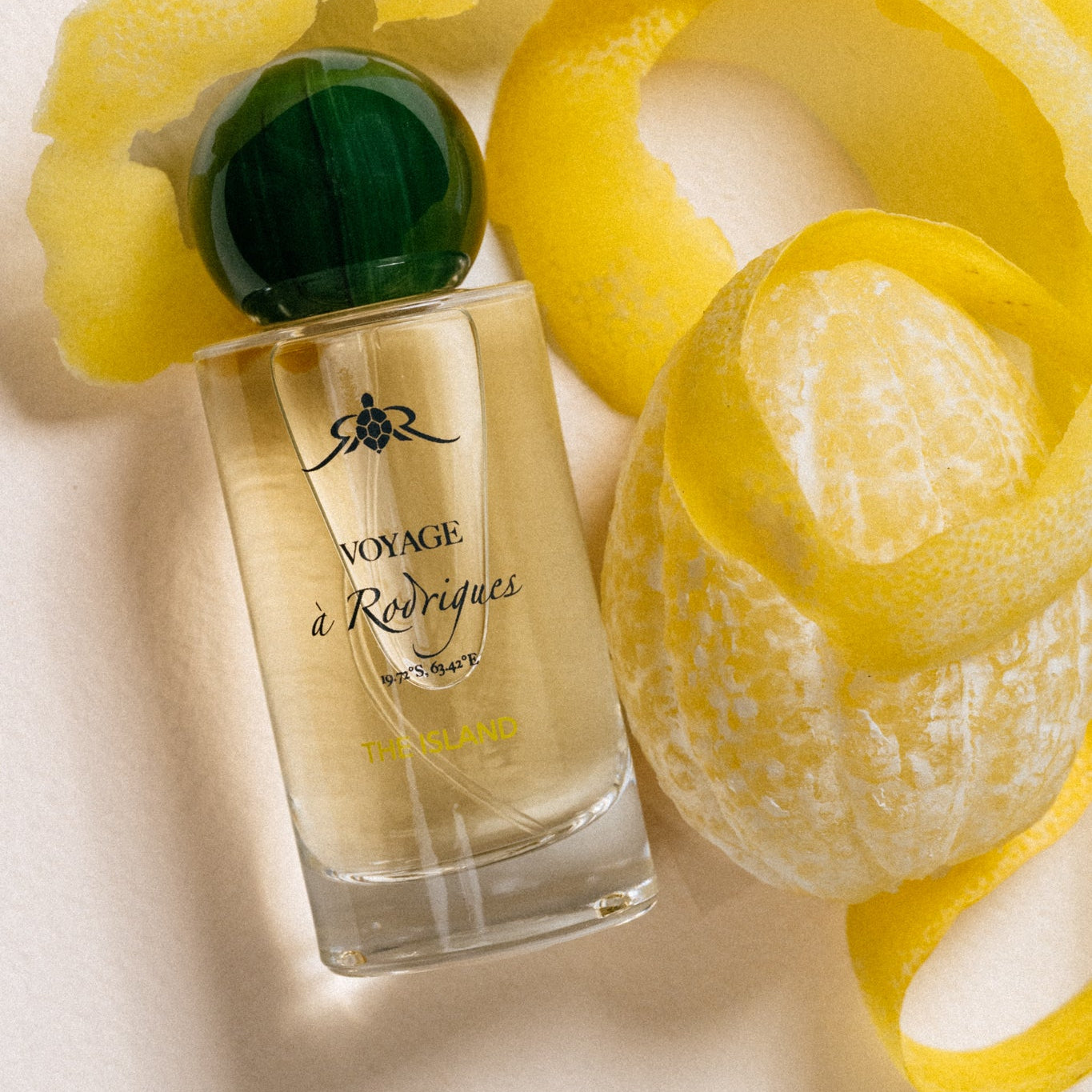 The Island - Eaux de parfums  Perfume bottle with green cap and yellow peel on a light background