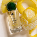 The Island - Eaux de parfums  Perfume bottle with green cap and yellow peel on a light background