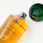 Orange perfume bottle labeled 'Voyage de Rodrigues' on a white background
