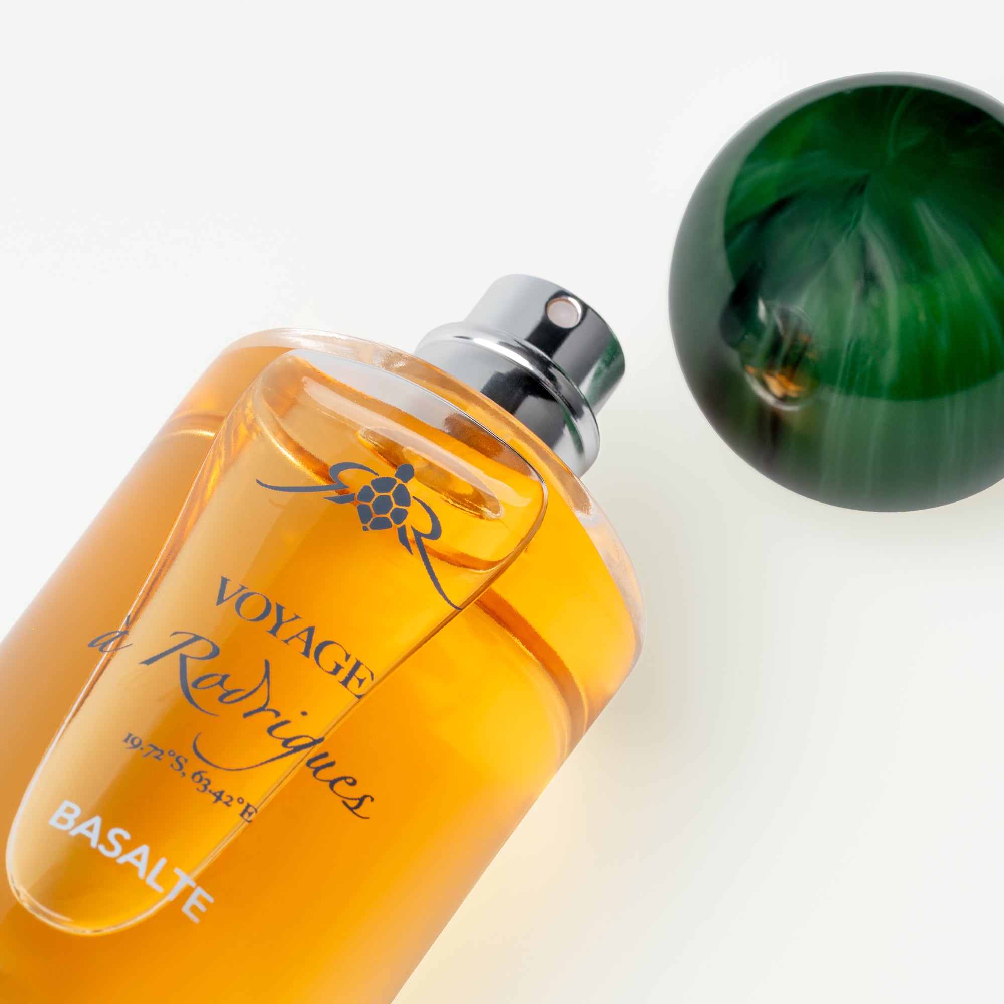 Orange perfume bottle labeled 'Voyage de Rodrigues' on a white background