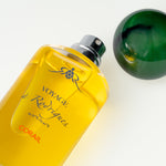 Yellow perfume bottle labeled 'Voyage de Rodrigues' on a light background