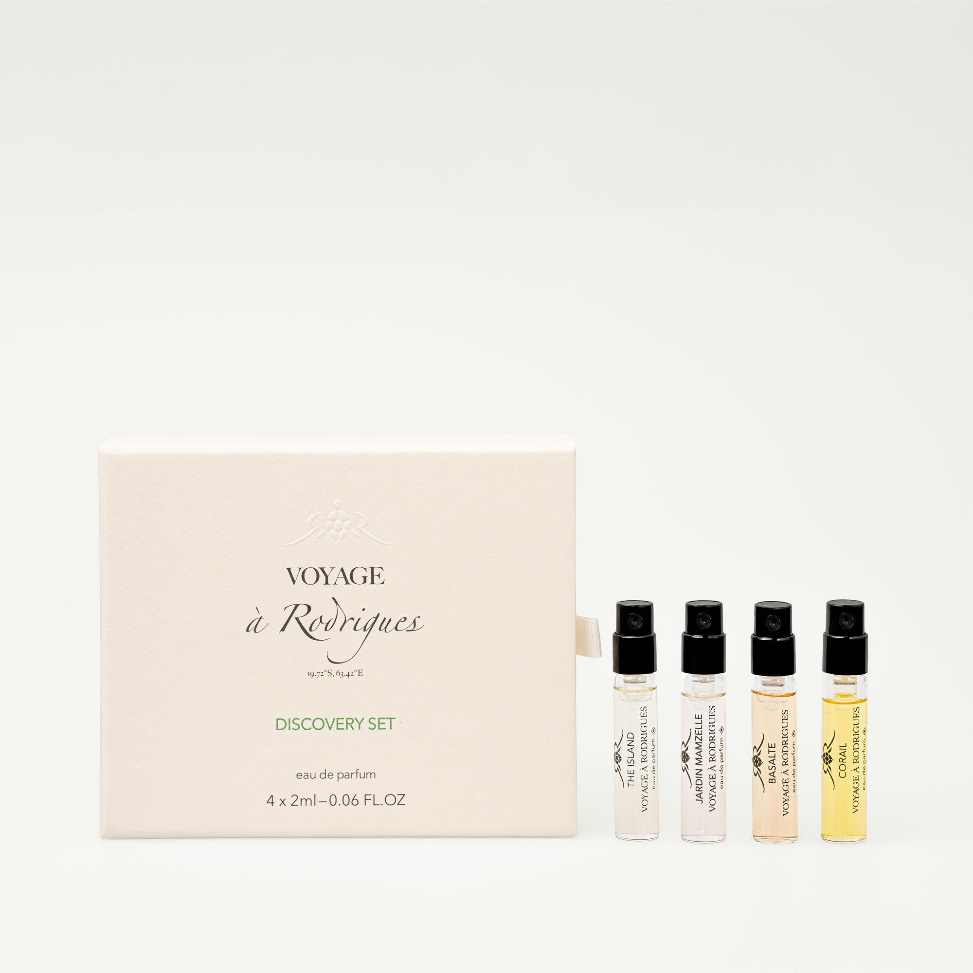 Set of four small perfume bottles with a box labeled 'Voyage à Rodrigues' on a white background.